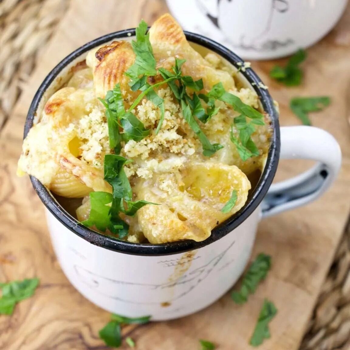 Delicious French onion pasta bake with melted cheese and herbs in a mug.